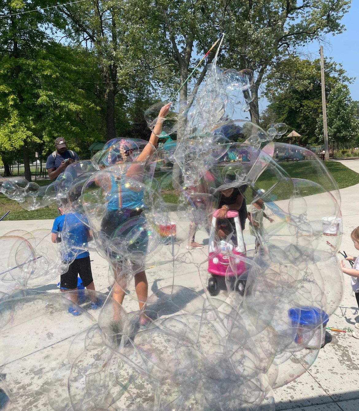 Large iridescent bubble domes with children playing in a park